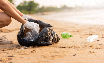 志愿者女人挑选塑料瓶<strong>垃圾</strong>塑料袋黑色的清洁海滩
