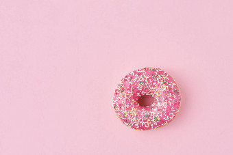 甜甜圈装饰洒糖衣粉红色的背景有创意的极 简食物概念前视图平躺