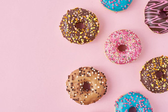 模式类型色彩斑斓的甜甜圈装饰洒糖衣柔和的粉红色的背景前视图平躺