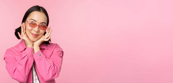 肖像时尚的可爱的亚洲女孩微笑触碰脸梦幻深思熟虑的站粉红色的背景