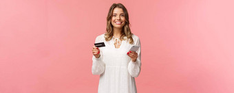 肖像快乐微笑金发碧眼的女人订单食物在线应用程序购物互联网商店持有信贷卡智能手机咧着嘴笑很高兴相机粉红色的背景