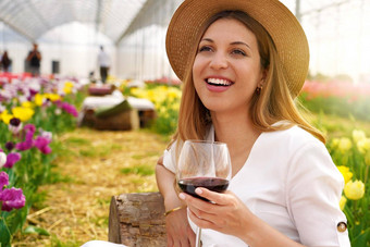 图像笑明亮的女人坐着花花园户外酒吧持有酒玻璃春天