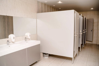 室内公共厕所。。。行洗盆地金属水龙头大理石板液体肥皂分配器长镜子灰色的墙