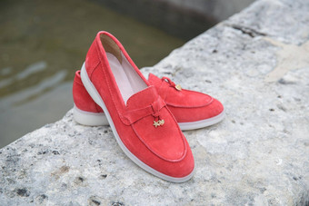 女人的红色的时尚的仿麂皮游手好闲的人鞋子石头背景一对时尚的女休闲鞋鞋子在户外