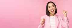 热情的女售货员亚洲企业女人实现目标庆祝并喜乐微笑站粉红色的背景