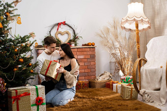 查看安排礼物包夫妇爱礼物坐在圣诞节树独特的圣诞节大气