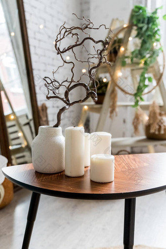 白色蜡烛木咖啡表格舒适的生活房间室内时尚的斯堪的那维亚生活房间蜡烛植物花瓶小木表格前面斯堪的那维亚设计沙发放荡不羁的首页室内装饰