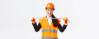 兴奋乐观的亚洲女建设<strong>工程师测量</strong>布局持有磁带<strong>测量</strong>微笑准备好了工作构建站白色背景安全头盔
