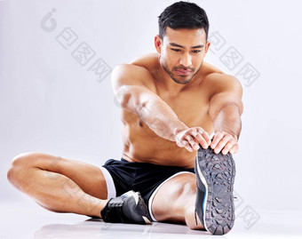 准备好了<strong>硬核</strong>锻炼拍摄年轻的男人。伸展运动腿工作室背景