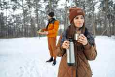 年轻的女人热喝热水瓶冬天森林
