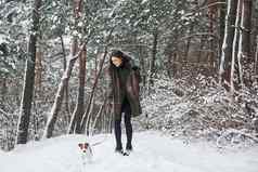 可爱的宠物在户外女人温暖的衣服走狗雪森林前面视图