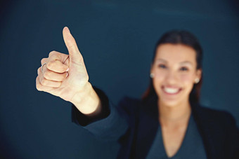 积极的的态度使成功的企业肖像年轻的女商人显示拇指黑暗背景