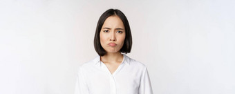 伤心悲观的年轻的亚洲女人扮鬼脸皱着眉头心烦意乱使撅嘴脸白色背景
