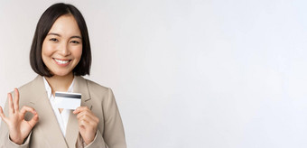 微笑办公室职员亚洲企业女人显示信贷卡标志<strong>推荐</strong>银行站白色背景米色西装
