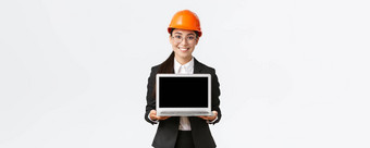 微笑专业女亚洲工程师介绍建设计划投资者客户站安全头盔西装显示移动PC屏幕很高兴微笑白色背景