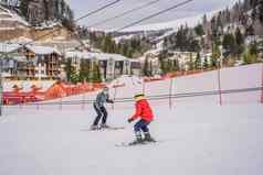 男孩学习滑雪培训听滑雪教练坡冬天