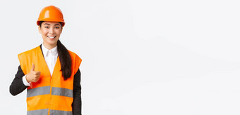 自信满意亚洲女建设经理安全头盔反光夹克显示竖起大拇指批准支持工作员工站白色背景