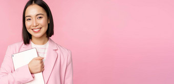 图像年轻的朝鲜文企业女人首席执行官经理持有数字平板电脑微笑专业穿西装站粉红色的背景