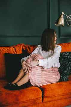 肖像时尚年轻的女人米色裙子白色上衣时尚的米色黑色的seude鞋子扣摆姿势橙色沙发