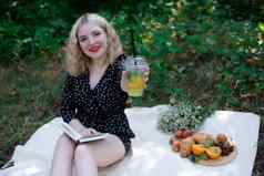 肖像年轻的女人野餐格子公园阅读书美味的零食