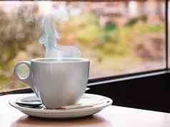 关闭白色咖啡杯酒吧表格窗口背景热气腾腾的杯咖啡