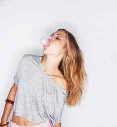 泡沫鼓风机时尚的年轻的女人吹泡沫咀嚼口香糖白色背景
