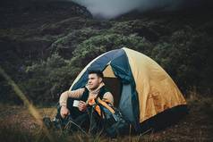经历内部睡觉拍摄年轻的男人。喝咖啡野营荒野