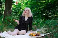 漂亮的金发女郎女孩野餐森林公园柠檬水水果羊角面包夏季休息放松千禧一代
