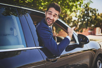 工作好友拍摄快乐的年轻的商人挂车窗口指出手前面车