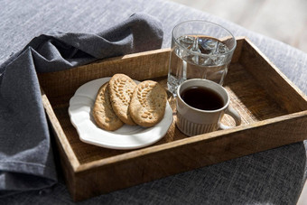 白色杯咖啡玻璃水长白铜勺子扭曲的处理飞碟柠檬早餐木托盘破布餐巾灰色的沙发