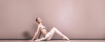 年轻的美丽的优雅的高加索人芭蕾舞女演员实践芭蕾舞职位图图裙子经典芭蕾舞舞者坐着地板上芭蕾舞工作室