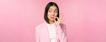 肖像亚洲企业女人显示口密封关闭关闭嘴唇关键手势承诺秘密站粉红色的背景西装