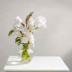 花束白色虹膜蕨类植物透明的花瓶表格