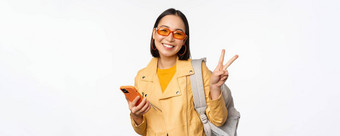 年轻的亚洲女人旅行者女孩旅游太阳镜持有背包移动电话应用程序智能<strong>手机</strong>站白色背景