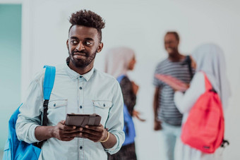 大学生活方式英俊的年轻的非洲学生男人。持有平板电脑电脑微笑站大学朋友团队会议背景高质量的照片