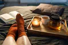 软照片女人腿羊毛袜子床上书杯茶蜡烛托盘室内首页舒适概念前视图