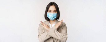 冠状病毒工作场所概念图像亚洲女商人女医疗脸面具显示停止交叉禁止手势站白色背景