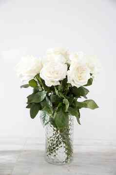 花束白色玫瑰玻璃花瓶米色表格灰色的墙复制空间