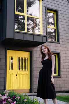 快乐年轻的女人黑色的衣服前面现代建筑黄色的通过乔迁庆宴购买房子快乐生活私人房子首页