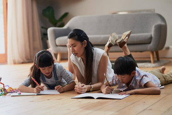 妈妈使孩子们家庭作业拍摄快乐的妈妈。孩子们家庭作业说谎地板上首页一天