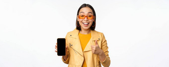 美丽的朝鲜文女孩亚洲女人太阳镜显示智能手机应用程序接口拇指推荐移动电话应用程序白色背景