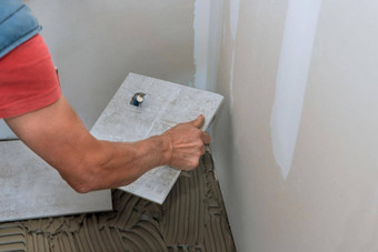 工人手应用瓷砖胶粘剂地板上过程铺设陶瓷瓷砖