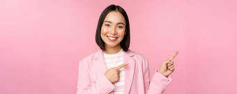 热情的专业女商人女售货员指出手指显示广告公司标志摆姿势粉红色的背景