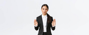 严肃的表情不高兴亚洲女经理女商人黑色的西装停止行动禁止限制提高手禁止手势白色背景