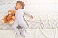 男孩大做梦的人高角拍摄婴儿男孩睡觉床上泰迪熊