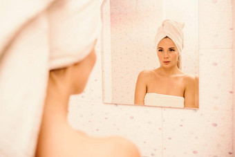 肖像年轻的女孩毛巾头白色浴室触摸脸镜子享受青年水合作用自然美首页护理问题皮肤