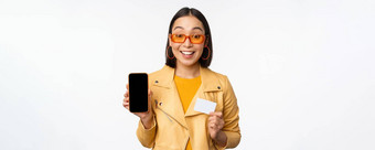 在线购物人概念时尚的亚洲女人显示移动电话屏幕信贷卡智能手机应用程序站白色背景