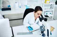 写作药物试验方法拍摄年轻的科学家写作笔记显微镜实验室