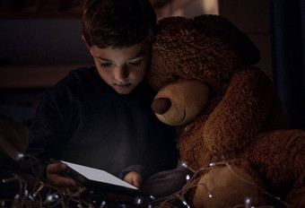 王国属于孩子们拍摄可爱的男孩数字平板电脑泰迪熊<strong>晚上卧室</strong>