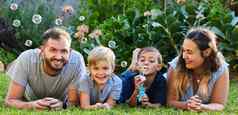 微笑孩子们礼物为人父母肖像美丽的家庭铺设草玩泡沫后院